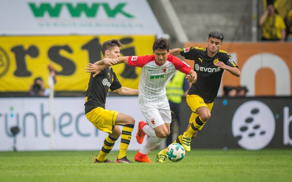 Ja-Cheol Koo (FC Augsburg) im Zweikampf mit den Dortmundern Julian Weigl und Mo Dahoud.